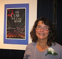 Alison Lohans with the poster of her book This Land We Call Home